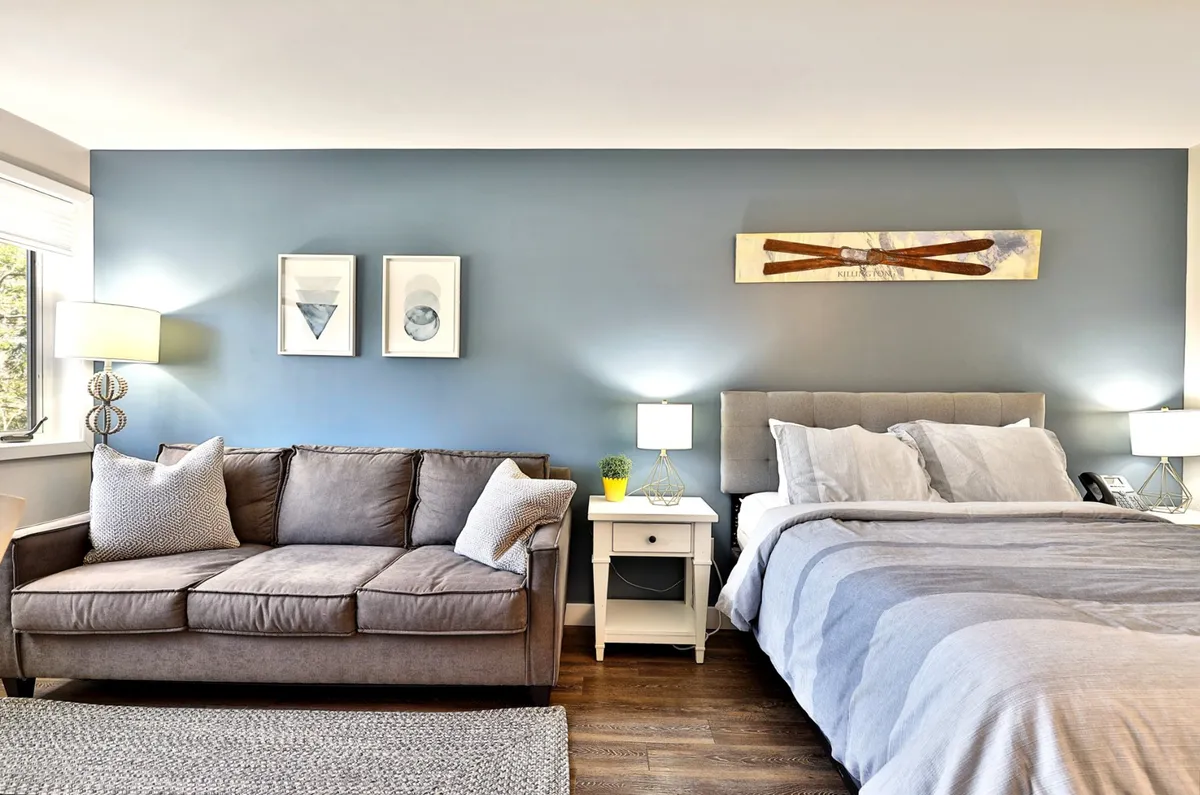 An inviting angle featuring a plush sofa, cozy bed, tasteful artwork, and stylish nightstands, all arranged to promote both relaxation and socialization. The serene, home-like feel makes it ideal for winding down after a productive day and enjoying quiet moments.